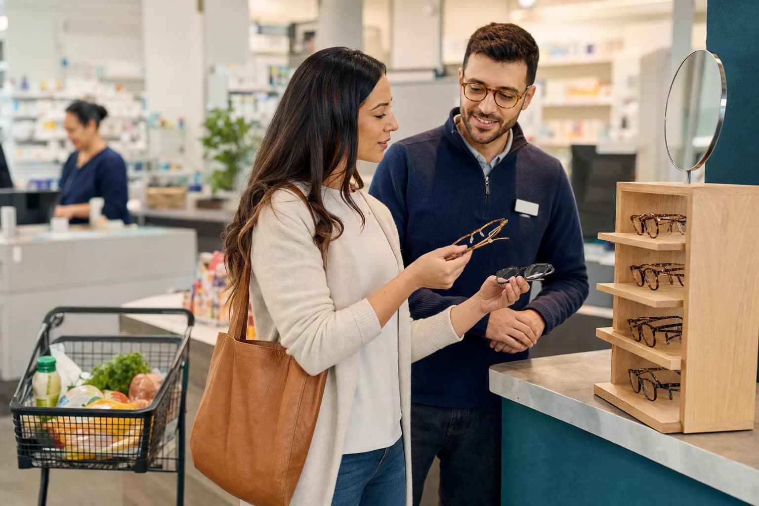 A customer and a store team member compare frames beside a pharmacy counter